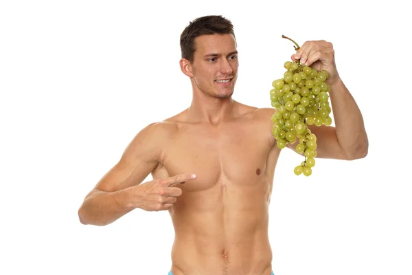 Homem sem camisa segura uvas — Fotografia de Stock