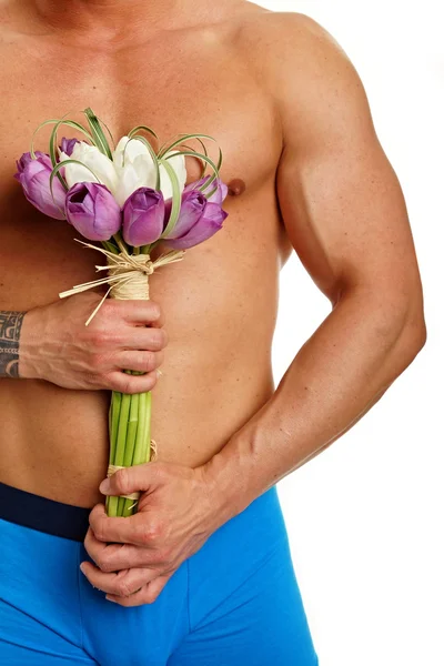 Muscular man holds bouquet of tulips — Stock Photo, Image
