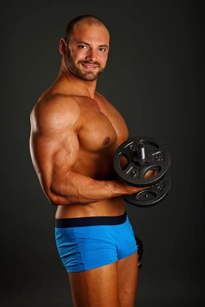 Muscular man exercises with dumbbell — Stock Photo, Image
