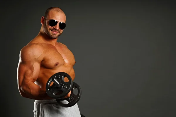 Muscular man exercises with dumbbell — Stock Photo, Image