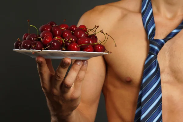 Hombre joven le muestra cerezas rojas frescas —  Fotos de Stock