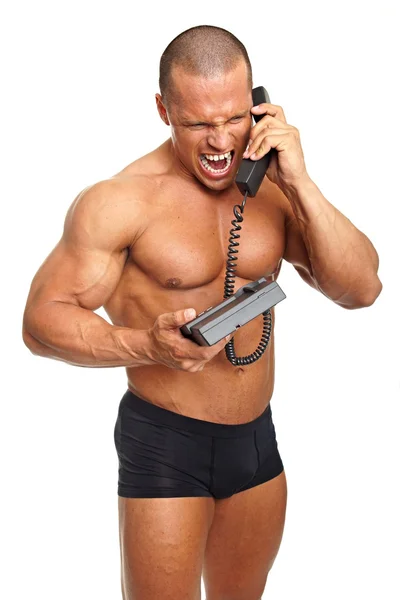 Muscular man speaks into telephone — Stock Photo, Image