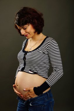 Hamile bir kadın karnını okşuyor.