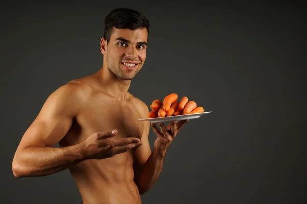 Sonriente hombre muestra zanahorias en el plato —  Fotos de Stock