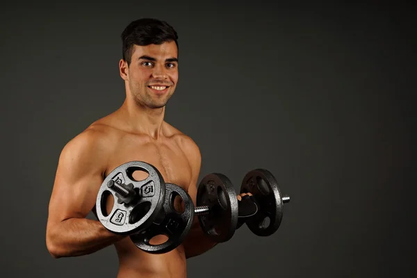 Muscular man exercises with dumbbells — Stock Photo, Image