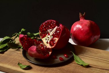 Nar ve yaprakları siyah arka planda durgun bir hayat..