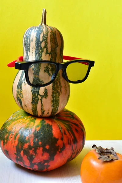 Pumpkin in glasses and persimmon on a yellow background. — Stock Photo, Image