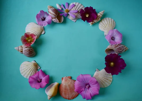 Wreath of sea shells and flowers on a blue background