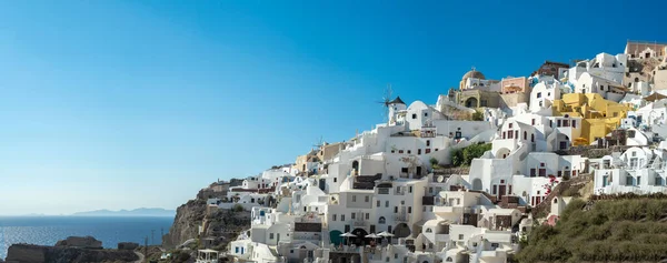 stock image Panoramic view of Oia town in Santorini island with old whitewashed houses and traditional windmill, Greece Greek landscape on a sunny day