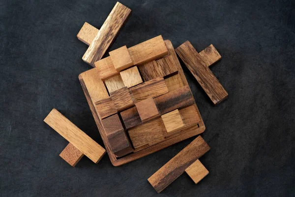 Wooden block brain teaser on dark background. Pieces Close Up. Top view