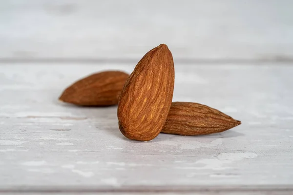 Close Three Isolated Almonds Standing White Wooden Table White Background — Stock Photo, Image