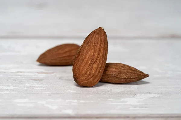 Close Three Isolated Almonds Standing White Wooden Table White Background — Stock Photo, Image