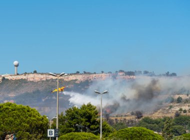 Marignane Havaalanı yakınlarındaki Marsilya tepelerinde yangın başladı. Sarı itfaiye uçağı üzerine su atıyor..