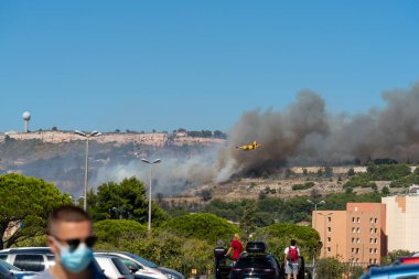 Marignane Havaalanı yakınlarındaki Marsilya tepelerinde yangın başladı. Sarı yangın söndürme uçağı üzerine su atacak..