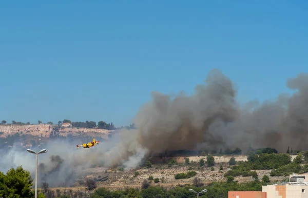 fire starts on the hills of Marseille, near Marignane airport. yellow fire-fighting plane is going to throwing water on it.