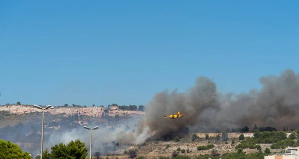 fire starts on the hills of Marseille, near Marignane airport. yellow fire-fighting plane is going to throwing water on it.