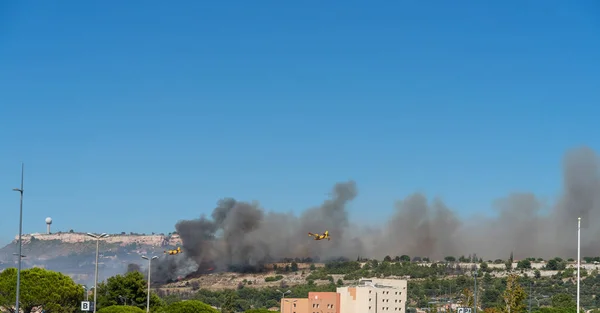 fire starts on the hills of Marseille, near Marignane airport. two yellow fire-fighting planes are going to throwing water on it.