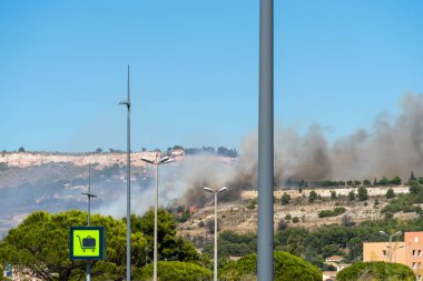 Marignane Havaalanı yakınlarındaki Marsilya tepelerinde yangın başladı. Gökyüzü mavi. Yakın tehlike