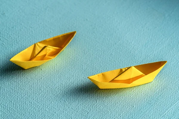 Origami yellow sailing boat on a sea made with blue paper. Paper art style background with ship and ocean.top view shot