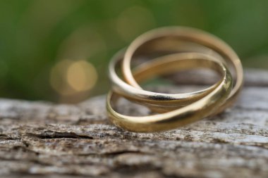 Ahşap zemin üzerinde üç halka olan bir yüzüğün yakın çekimi. Altın, beyaz altın ve gül sarısı düğün mücevherleri. seçici odak ile makro çekim ve metin için boşluk kopyala