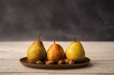 Koyu arka planda, tahtadan bir fındıklı üç armut. sağlıklı yeme kavramı