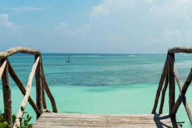 Tanzanya 'daki Zanzibar tropikal adasında ahşap merdivenleri olan şaşırtıcı bir turkuaz göl. Geleneksel tekne denizde yüzüyor.