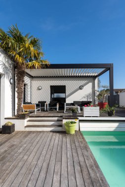 Modaya uygun teras pergola yapısı, tente ve teras çatısı, bahçe salonu, sandalyeler, peyzaj ile çevrili metal ızgara. portre biçimi