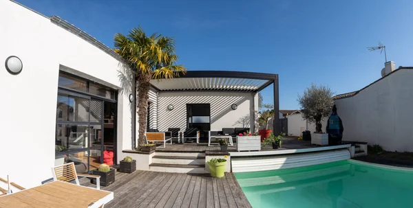 Modern ev, tente ve teras, bahçe salonu, sandalyeler, bahçe düzeniyle çevrili metal ızgara.