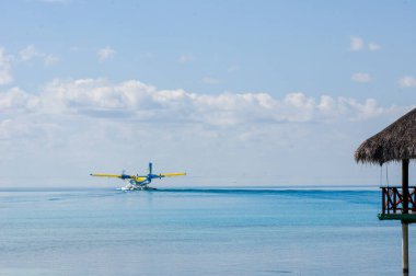 Bir deniz uçağının turkuaz maldivya gölüne inmesi. Lüks seyahat konsepti