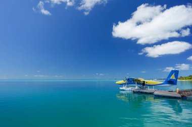 Turkuaz maldivian lagünündeki mavi ve sarı deniz uçağı. Lüks seyahat konsepti