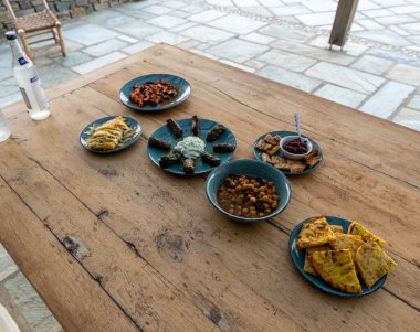 Yunan yemeği. Pita, tzatziki, doldurulmuş üzüm yaprağı, nohut salatası ve sebze, uzo şişesi. Geleneksel Yunan yemekleri seti. Paylaşmak için yiyecek. Üst görünüm Yakın plan.