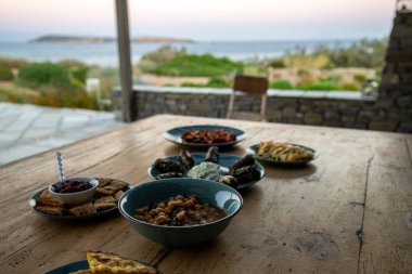 Yunan yemeği. Meze, gyros, souvlaki, pide, Yunan salatası, tzatziki, nohut salatası ve sebze. Geleneksel Yunan yemekleri seti. Paylaşmak için yiyecek. Yakın plan. Arka planda deniz manzarası