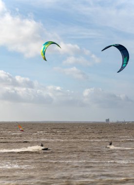 Bilinmeyen uçurtmacılar, Fransa 'nın La Rochelle kentindeki Atlantik Okyanusu' ndan gelen dalgalarla kahverengi sularda sörf yapıyor..