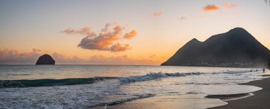 Martinique sahilinden Diamond Rock 'ın günbatımı manzarası, yumuşak okyanus dalgaları, sıcak altın ışık, tropikal bulutlar ve huzurlu Karayip deniz manzarası. pankart biçimi