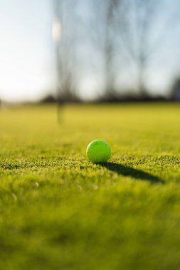 Golf topu yeşilde. Golfçü topu yeşile atıyor. Yeşil arkaplanı olan bir pimi kapat. Top yüzey yaşam tarzında.