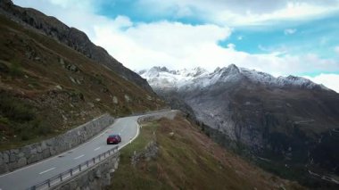İsviçre Alplerinde dağ yolunda giden elektrikli spor araba. Yüksek kalite 4k drone görüntüsü