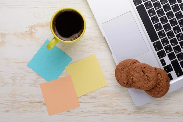 Laptop and notes with a cup of coffee and snacks on table — Stock Photo, Image