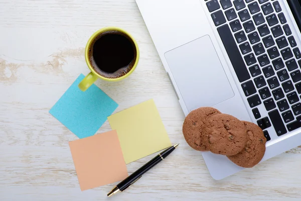 Laptop and notes with a cup of coffee and snacks on table — Stock Photo, Image