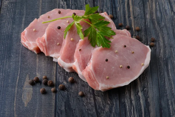 Raw meat steak on wooden board with pepper — Stock Photo, Image