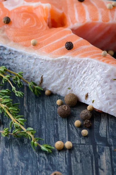 Salmão cru com tomilho e pimenta em uma tábua de madeira. close-up — Fotografia de Stock