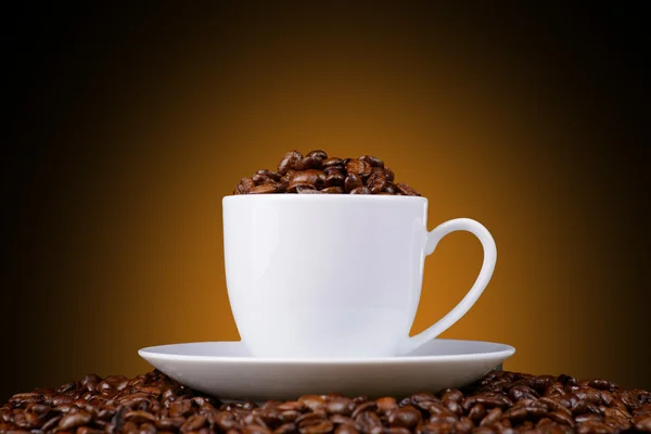 turuncu bir arka plan üzerinde beyaz bir fincan kahve çekirdekleri