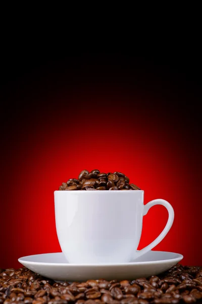 赤の背景に白いカップでコーヒー豆 — ストック写真