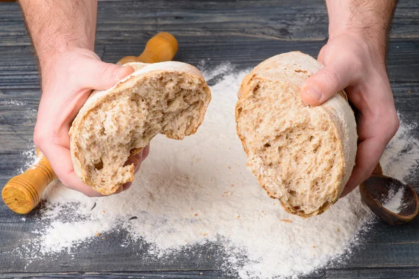 Het gebroken brood in mannelijke handen — Stockfoto