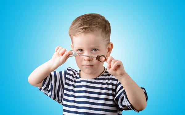 mavi bir arka plan üzerinde kelepçe ile küçük çocuk