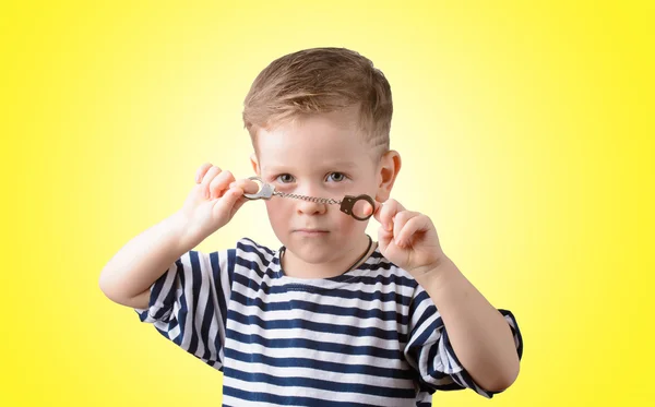 Sarı bir arka plan üzerinde kelepçe ile küçük çocuk