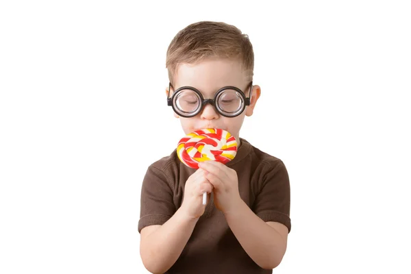 Little boy eating a piece of candy in glasses — Stock Photo, Image