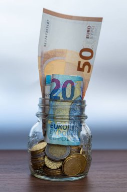 Tahta yüzeyde ve şeffaf bir kavanozda tasarruf, para ve banknotlar. Para kaydedildi.