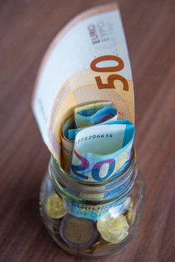 Tahta yüzeyde ve şeffaf bir kavanozda tasarruf, para ve banknotlar. Para kaydedildi.