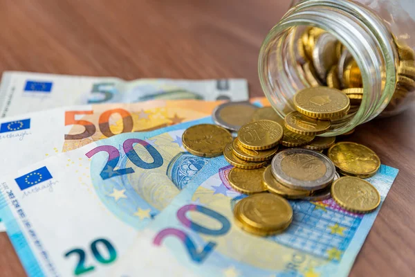 Tahta yüzeyde ve şeffaf bir kavanozda tasarruf, para ve banknotlar. Para kaydedildi.