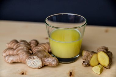 Zencefil suyu, yanında zencefil kökü, ahşap bir yüzey üzerinde.